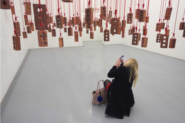 A visitor takes photos of an artwork by South African artist Kendell Geers, during the media opening of the Zeitz Museum of Contemporary Art Africa on September 15, 2017 in Cape Town.