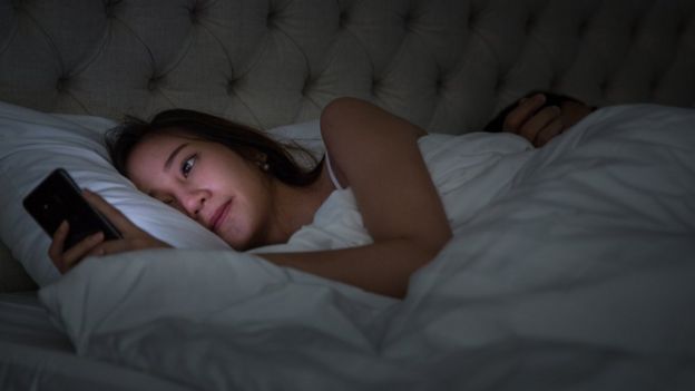 Mujer en la cama con el teléfono