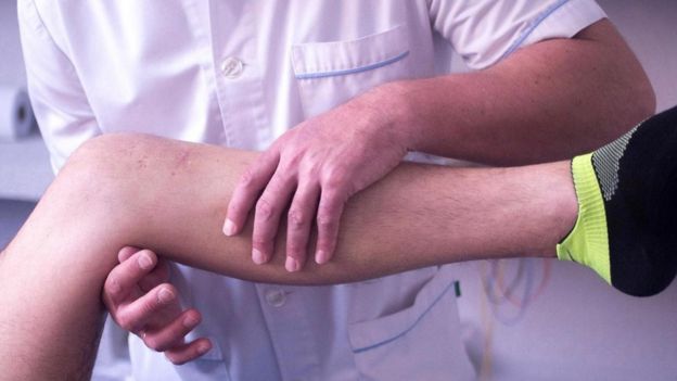 طبيب يعالج طفلا ويمسك بإحدى رجليه