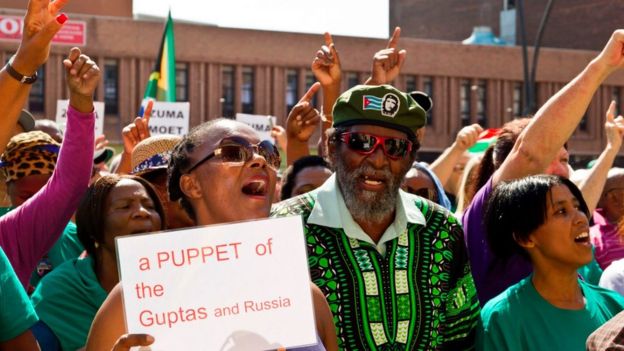 Protesters hold signs criticising President Zuma's links to the Gupta family and to Russia in Port Elizabeth, South Africa (04 April 2017)