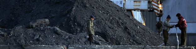 Empleados de Corea del Norte trabajan junto al río Yalu en la ciudad norcoreana de Sinuiju el 8 de febrero de 2013, que está cerca de la ciudad china de Dandong. Se ven pilas de carbón.