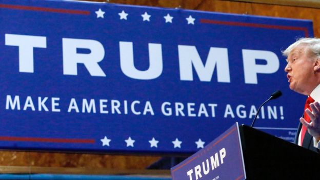 Donald Trump speaks in front of a 