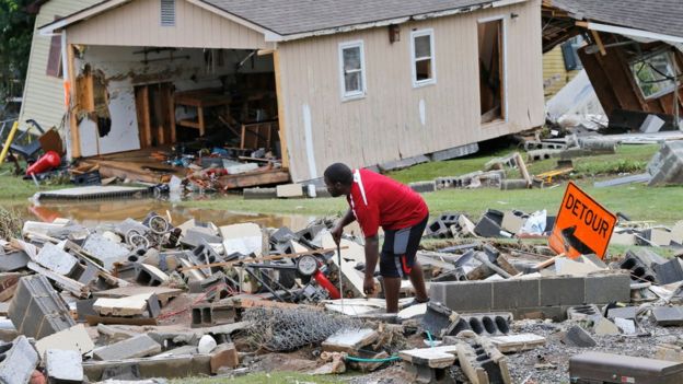 A resident sorts through debris as the cleanup begins from severe flooding in West Virginia on 24 June