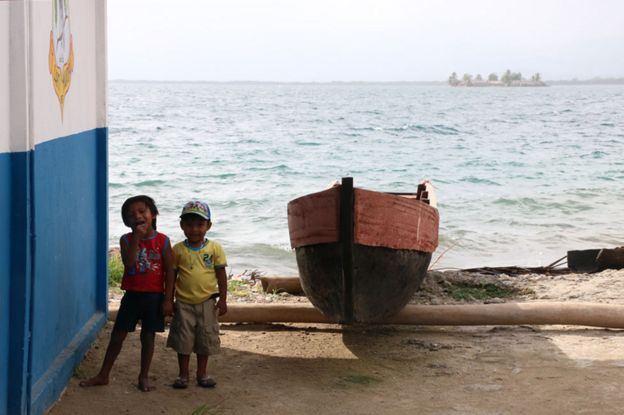 Niños gunas junto a una canoa