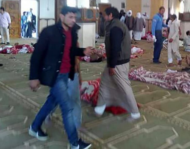 Egyptians walk past bodies following a gun and bombing attack at the Rawda mosque, roughly 40 kilometres west of the North Sinai capital of El-Arish, on November 24, 2017.