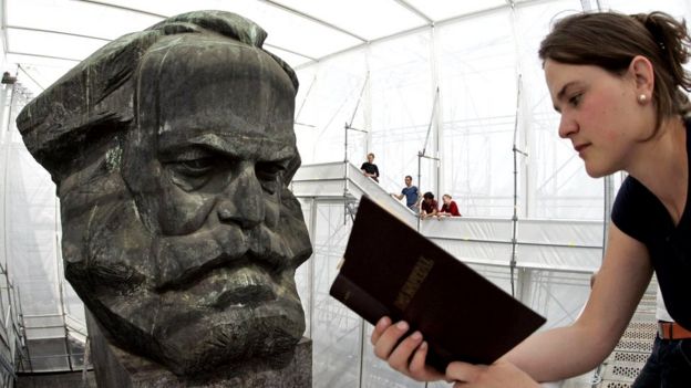 Una joven alemana lee "El capital" frente a un busto de Marx
