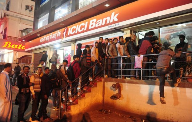 Indians queue to withdraw money from an ATM