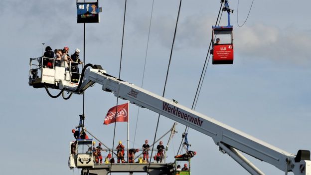 German fire crews evacuate trapped passengers from suspended cable cars that run over the river Rhine after a gondola ran into a support pillar in Cologne, Germany, 30 July 2017