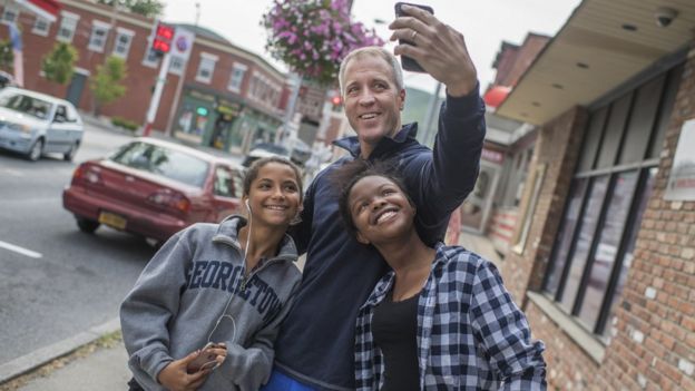 Un padre con sus dos hijas tomándose una selfie.