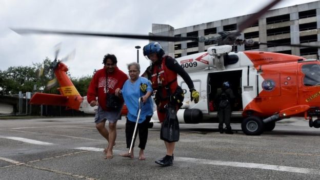 Evacuees exit a US Coast Guard helicopter that rescued them after Hurricane Harvey inundated the Texas Gulf coast with rain and flooded their home in Houston (27 August 2017)