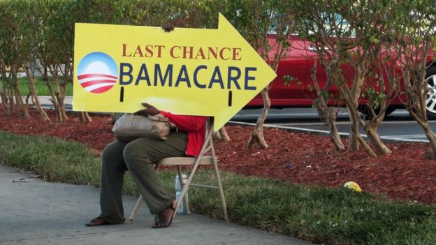 Una mujer con un cartel para registrarse en Obamacare