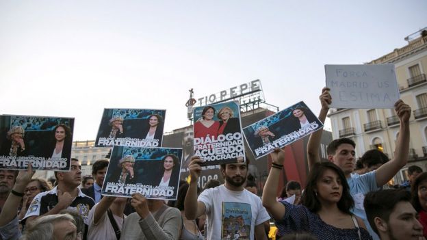 Los manifestantes en la Puerta del Sol de Madrid muestran el retrato de Carmena y Colau.