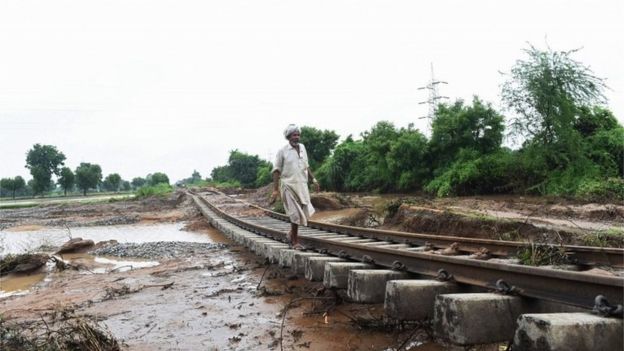 Inthis photograph taken July 29, 2017 an Indian villager walks along damaged railway tracks due to floods at Godha village of Deesa taluka, some 195km from Ahmedabad.
