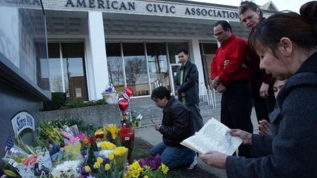 Un grupo de personas reza frente al centro comunitario de migrantes, en Binghamton, Nueva York, tras la masacre, en 2009.