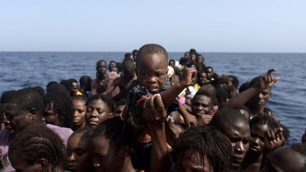 Un niño es levantado sobre la multitud que espera ser rescatada