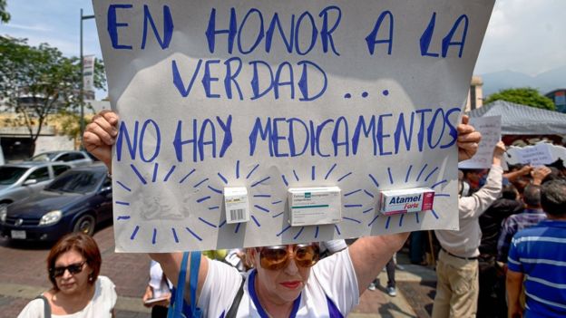 Una señora con una pancarta que denuncia la escasez de medicamentos