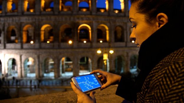 Mujer observa su celular en la noche