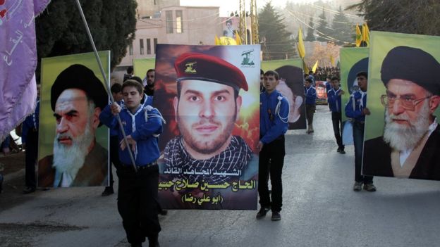 Banners showing the founder of the Islamic Republic of Iran, Ayatollah Ruhollah Khomeini (L), and the current Supreme Leader of Iran, Ayatollah Ali Khamenei (R), are held up beside one of a Lebanese Hezbollah commander killed in Syria (C) at a funeral in Baalbek (1 January 2014)