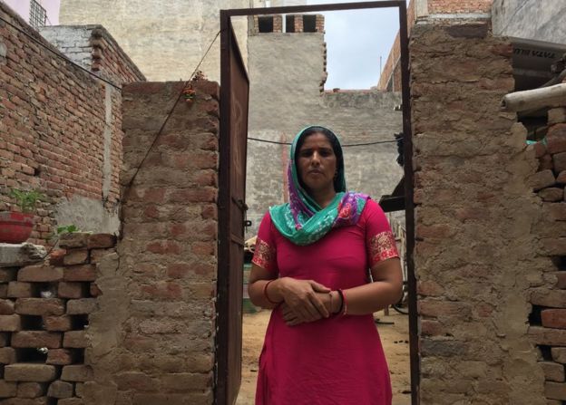 Munesh Devi standing front of a half-build house