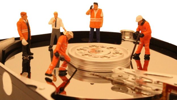 Trabajadores en miniatura trabajando en el disco duro de una computadora.
