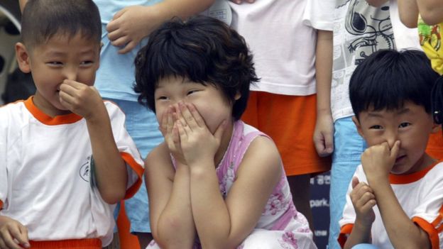Niños surcoreanos tapándose la boca.
