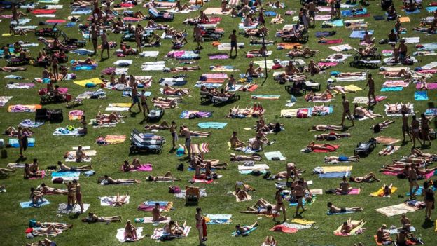People sunbathe in a park in Prague as temperatures reach 38C in parts of the Czech Republic, 1 August 2017