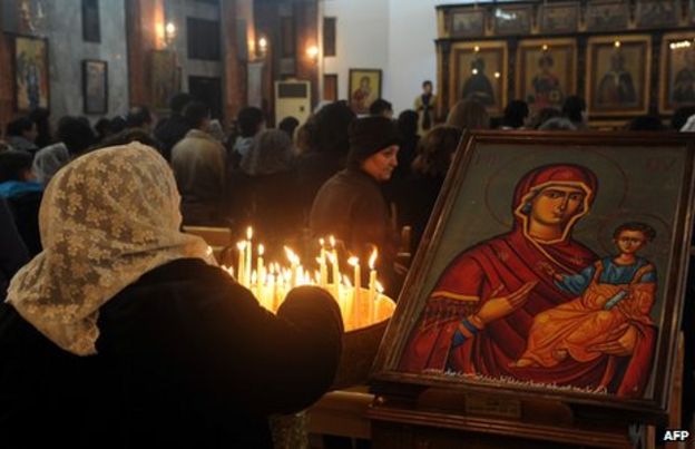 A Syrian woman lights candles as she attends Mass at the Mar Elias (St Elijah) Orthodox church in Bab Touma, Damascus (24 December 2012)