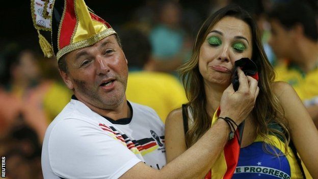 A Germany fan consoles a Brazil fan (R) during their 2014 World Cup semi-finals at the Mineirao stadium in Belo Horizonte