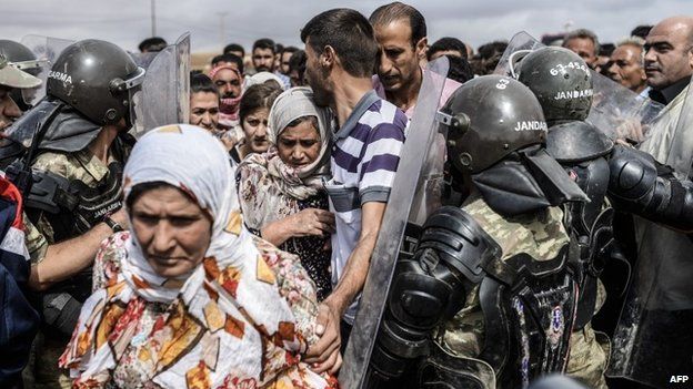 Turkish soldiers filter refugees crossing the border near the Syrian town of Kobane (28 September 2014)