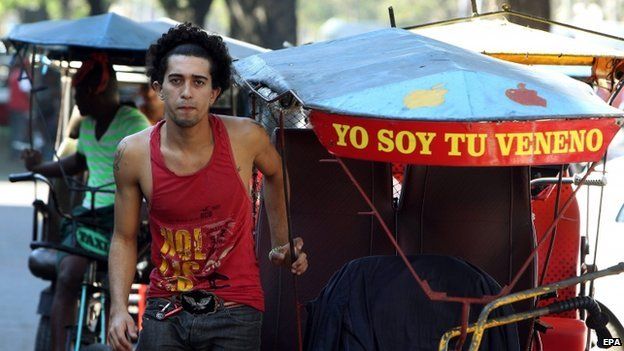 a man stands next to his cycle rickshaw in havana