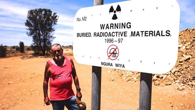 Robin Matthews, caretaker of the Maralinga Nuclear Test Site, stands beside a sign