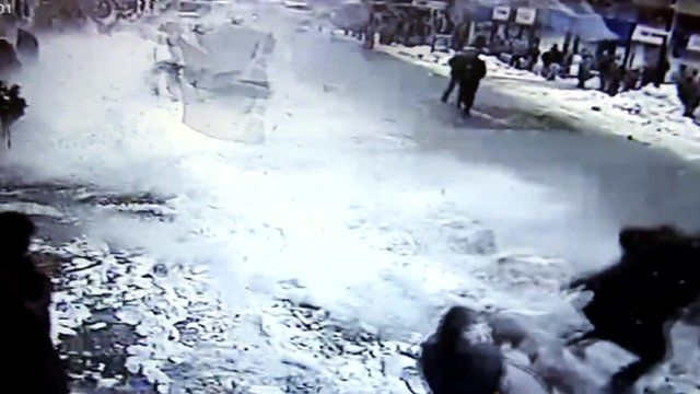 Chunks of snow fall off a roof onto pedestrians in Rize, Turkey