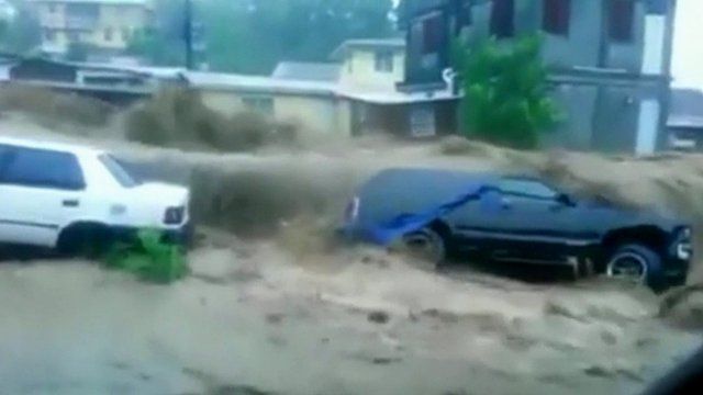 Floodwaters rush over cars