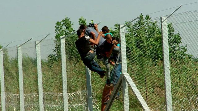 Afghan men breach the fence at Hungary's border