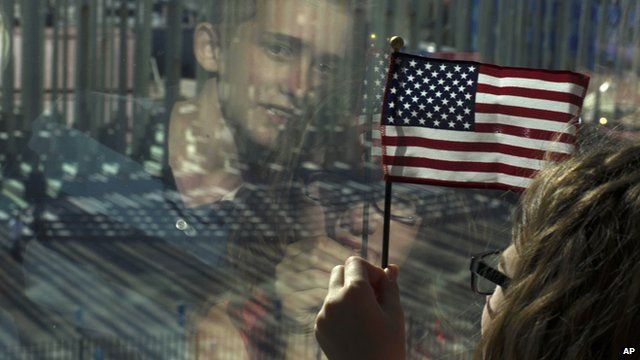 Girl with US flag and reflection of boy in window as they watch ceremony to mark reopening of US embassy in Havana