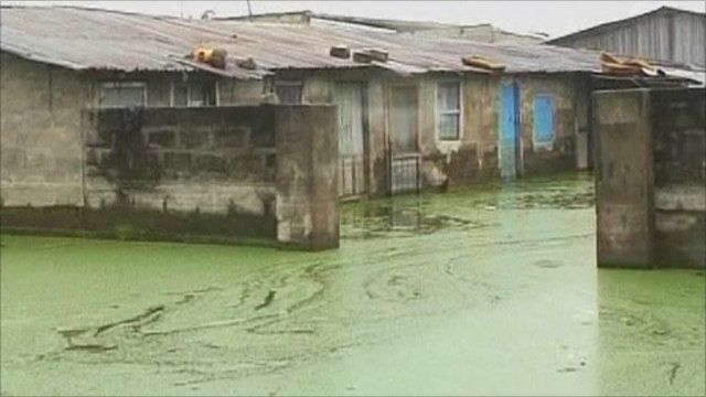 Green flood water surrounds buildings