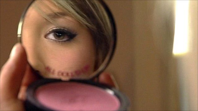 Girl applying make-up in mirror