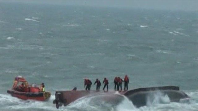 Passengers standing on the capsized boat