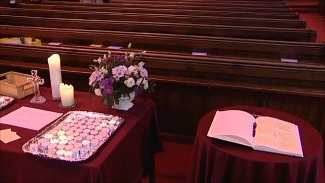 Book of condolence next to candles and flowers