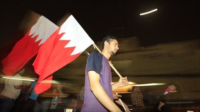 Bahraini anti-government protesters walk with national flag