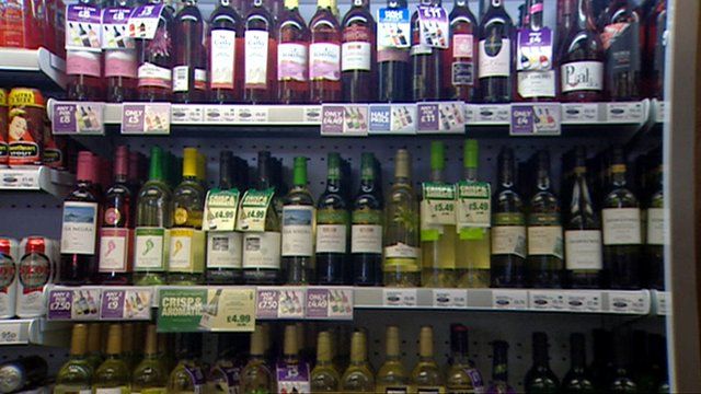 Bottles of wine and cans of beer on a supermarket shelf