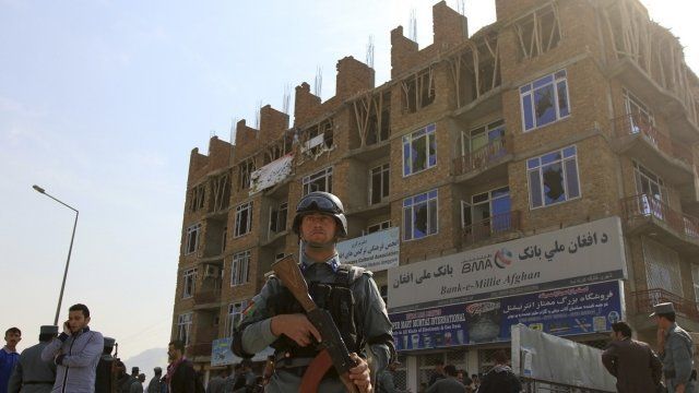 Afghan policeman stand guard after a battle with Taliban insurgents who took over a building in Kabul