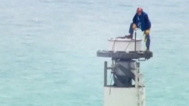 An engineer unscrews a TV antenna on top of the Willis Tower.