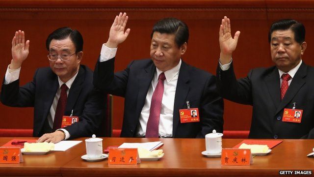 China"s Vice President Xi Jinping (C) raise his hand as he takes a vote during the closing session of the 18th National Congress of the Communist Party of China