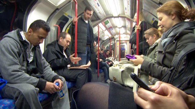 Rory Cellan-Jones reads his paper while other Tube commuters check their smartphones