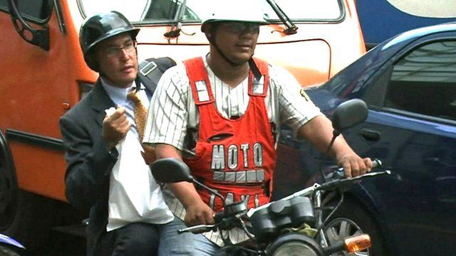 A taxi driver and his passenger on a motorbike taxi