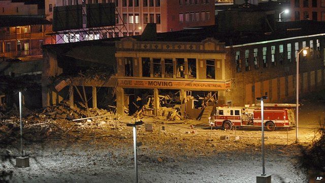 A fire truck is parked next to a damaged building after a nearby gas explosion levelled another building in Springfield
