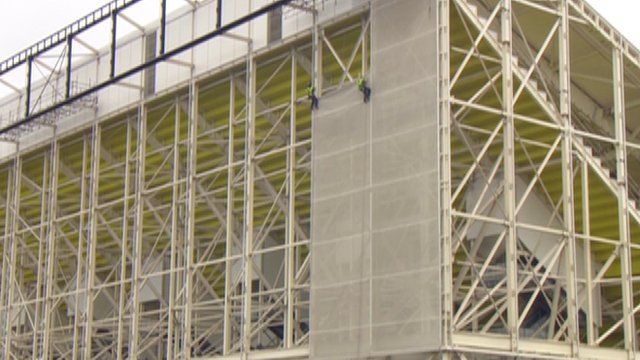 Workers at the Olympic Stadium dismantling wrapping