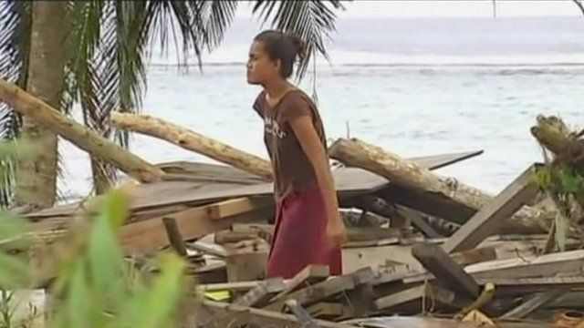 Woman standing in middle of debris made of remains of wooden building