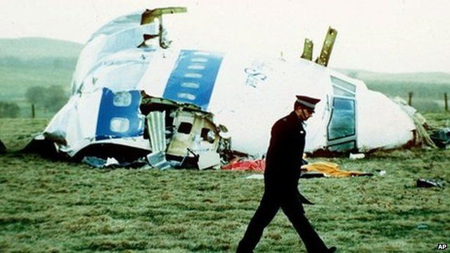 A police officer walks by the nose of Pan Am flight 103 in a field near the town of Lockerbie